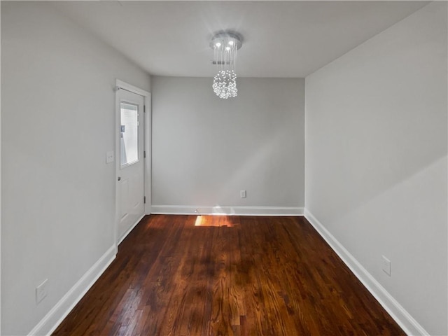 unfurnished dining area featuring wood finished floors, baseboards, and an inviting chandelier