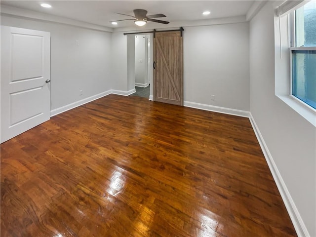 empty room featuring recessed lighting, a barn door, ceiling fan, wood finished floors, and baseboards