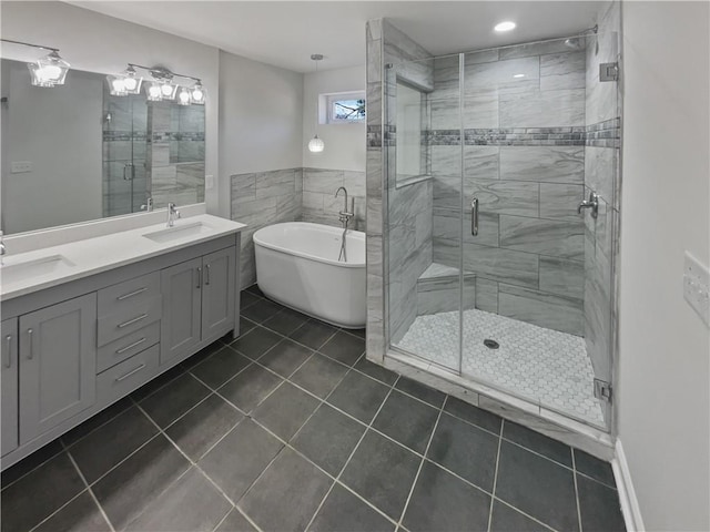 bathroom featuring a stall shower, a soaking tub, tile patterned flooring, and a sink