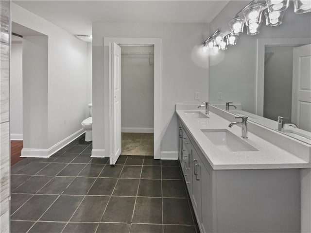 bathroom featuring toilet, baseboards, a sink, and tile patterned floors