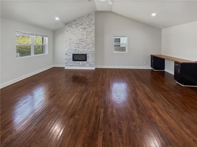 unfurnished living room with dark wood finished floors, a fireplace, built in desk, vaulted ceiling, and baseboards