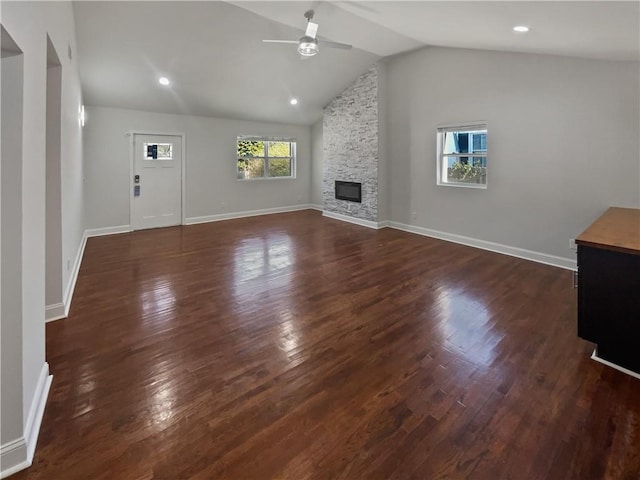 unfurnished living room featuring lofted ceiling, dark wood-style flooring, a fireplace, and a ceiling fan