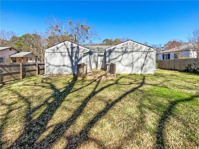 rear view of property featuring a lawn and a fenced backyard