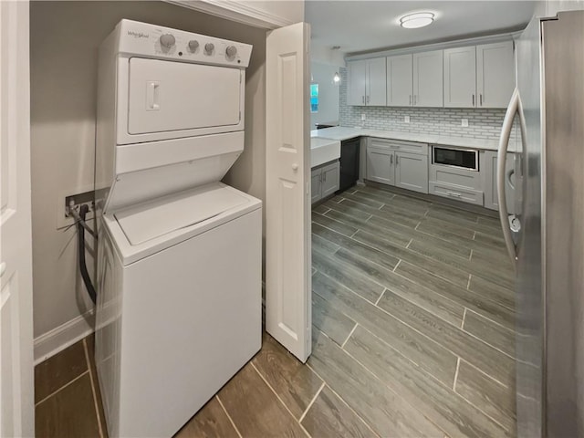 laundry room featuring laundry area, stacked washer and clothes dryer, and wood tiled floor