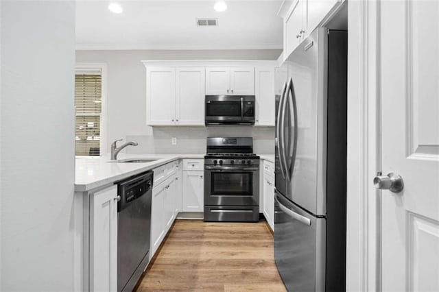 1283 Mercer, East Point, GA 30344 - kitchen with appliances with stainless steel finishes, light countertops, white cabinetry, light wood finished floors, and recessed lighting