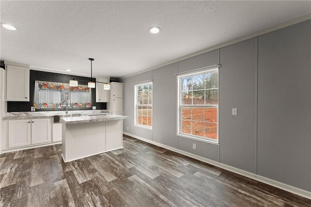 kitchen featuring pendant lighting, dark wood-type flooring, white cabinetry, a textured ceiling, and a kitchen island