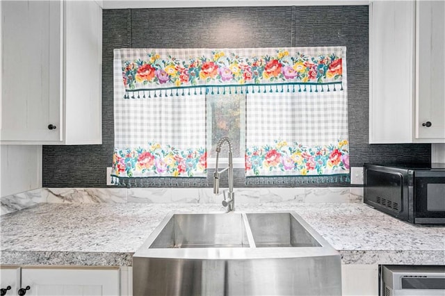 kitchen with tasteful backsplash, white cabinetry, and sink