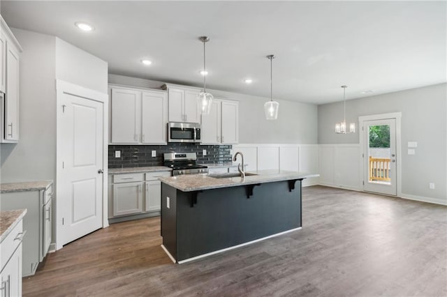 kitchen featuring a breakfast bar, appliances with stainless steel finishes, dark wood-type flooring, white cabinets, and a sink