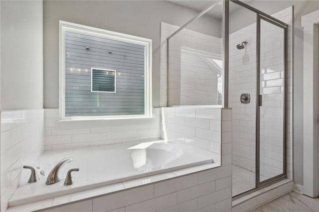 full bathroom featuring marble finish floor, a stall shower, and a bath