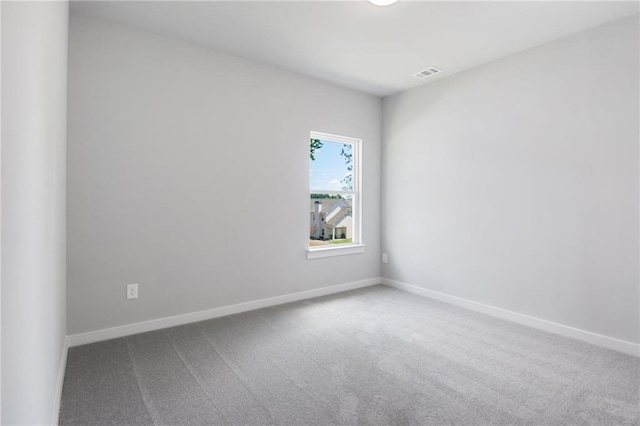 empty room with carpet, visible vents, and baseboards