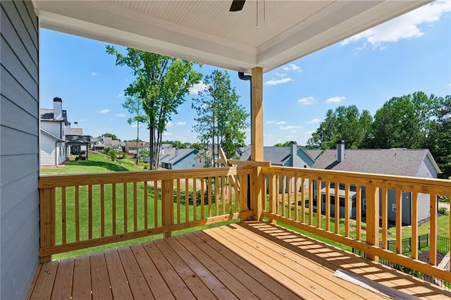 wooden deck with a residential view, a lawn, and ceiling fan