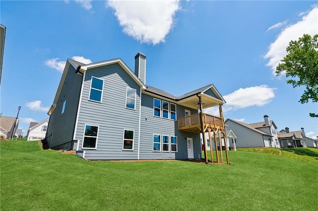 back of house with a ceiling fan, a lawn, and a chimney