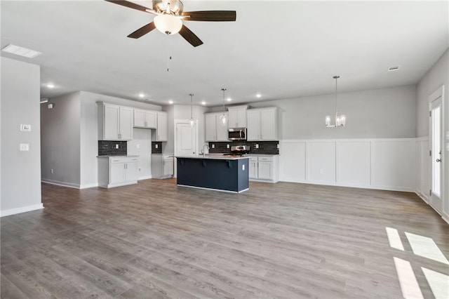 kitchen featuring open floor plan, tasteful backsplash, stainless steel microwave, and light wood-type flooring