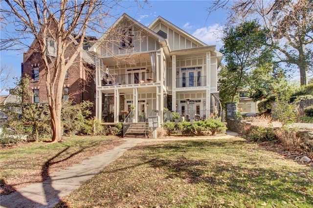 view of front of house featuring a balcony, french doors, and a front lawn