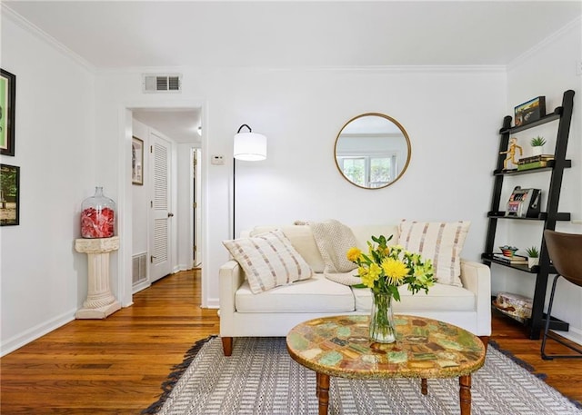 living area with ornamental molding, wood finished floors, visible vents, and baseboards