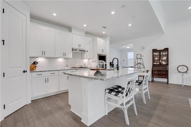 kitchen with light wood-type flooring, white cabinets, a sink, appliances with stainless steel finishes, and backsplash