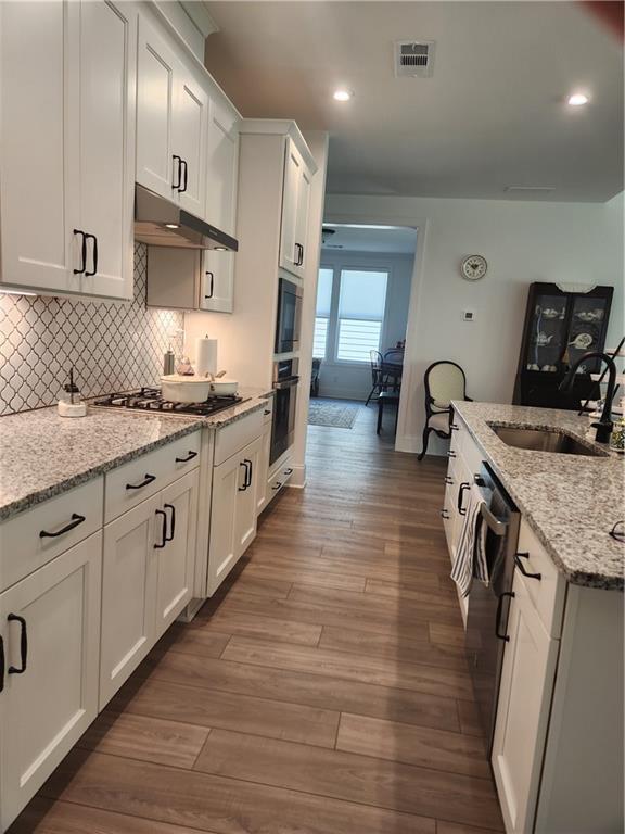 kitchen featuring visible vents, appliances with stainless steel finishes, a sink, white cabinets, and under cabinet range hood