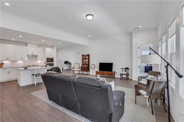 living area with recessed lighting, visible vents, and wood finished floors