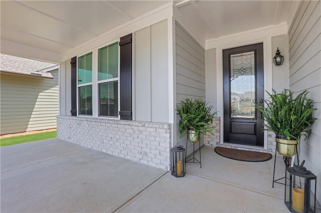 entrance to property with a porch and brick siding