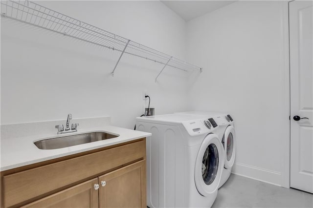 laundry area featuring a sink, baseboards, cabinet space, and washer and clothes dryer