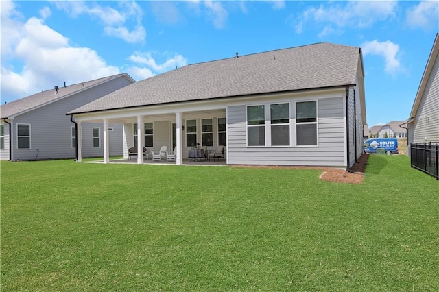 rear view of house featuring a lawn, fence, and a patio area