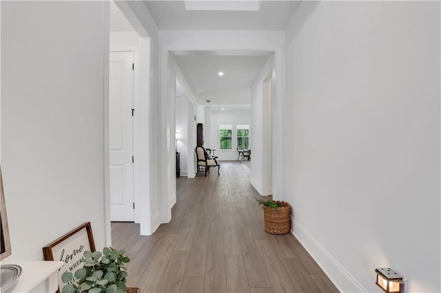 hallway with light wood-style floors, recessed lighting, and baseboards
