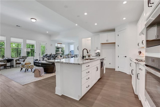 kitchen with stainless steel appliances, open floor plan, a sink, and wood finished floors