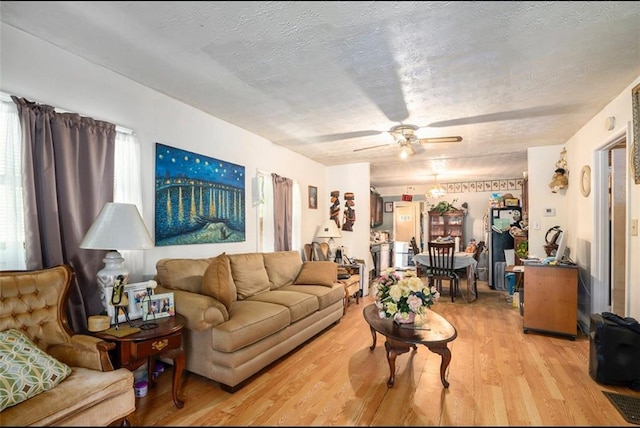 living room with a textured ceiling, ceiling fan, and hardwood / wood-style floors