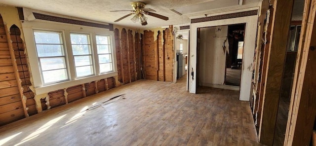 interior space featuring a textured ceiling, a ceiling fan, and wood finished floors