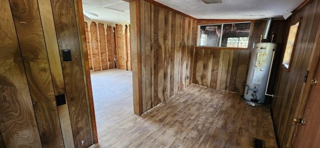 interior space featuring a textured ceiling, water heater, and wood finished floors