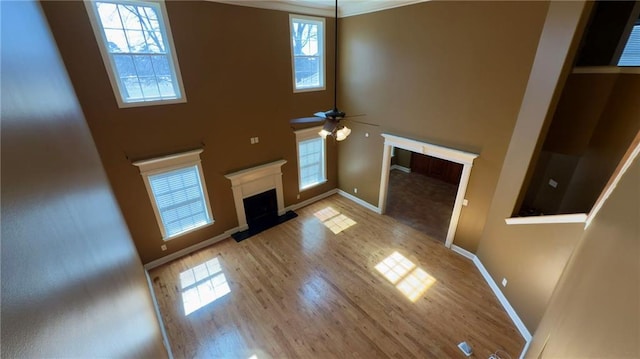 unfurnished living room featuring a fireplace, wood finished floors, a towering ceiling, and baseboards