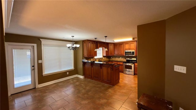 kitchen with a peninsula, appliances with stainless steel finishes, brown cabinets, dark countertops, and decorative light fixtures