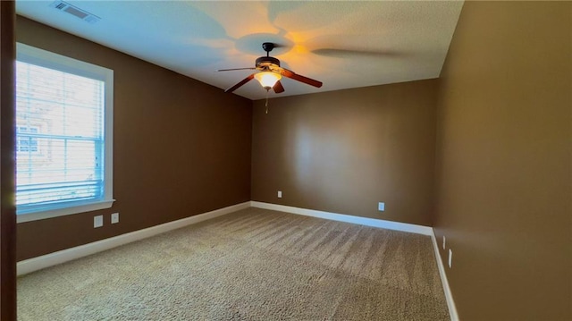 spare room featuring carpet floors, baseboards, visible vents, and a ceiling fan