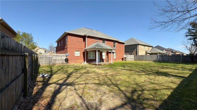 rear view of property with a fenced backyard, a gate, a lawn, and brick siding