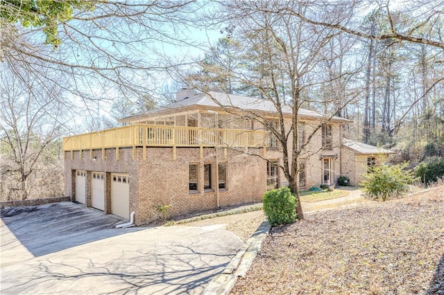 view of side of home featuring driveway, an attached garage, and brick siding