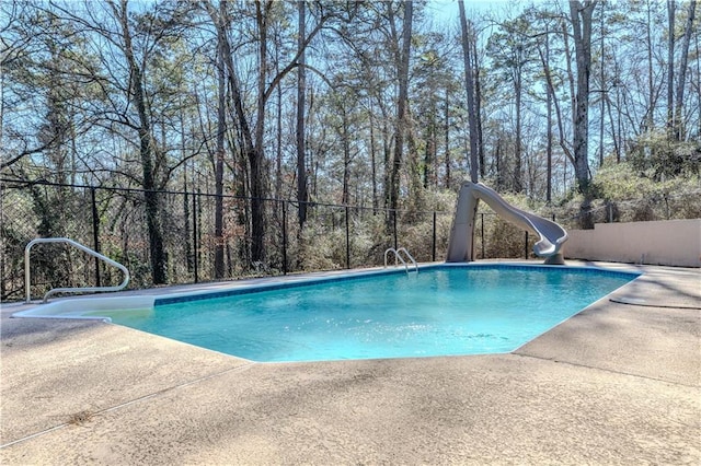 view of pool featuring a patio, a water slide, fence, and a fenced in pool