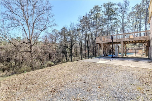 view of yard featuring gravel driveway, a deck, and stairs