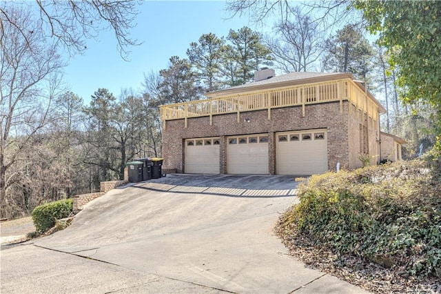 view of side of property featuring a garage, brick siding, a chimney, and aphalt driveway