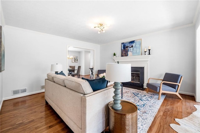 living area featuring a fireplace with flush hearth, wood finished floors, visible vents, and baseboards