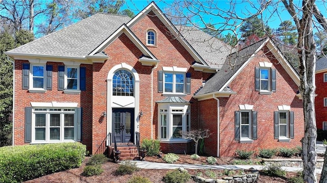 view of front of home with french doors, brick siding, and a shingled roof