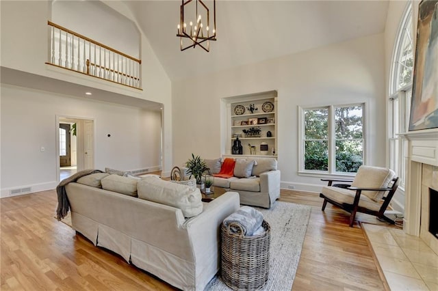 living area with visible vents, baseboards, light wood-style flooring, a fireplace, and high vaulted ceiling