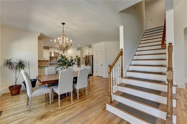 dining area with an inviting chandelier, baseboards, stairs, and light wood-style floors