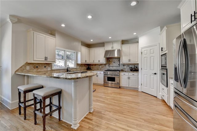 kitchen with under cabinet range hood, appliances with stainless steel finishes, a peninsula, and white cabinetry