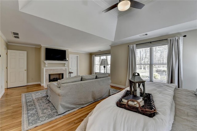 bedroom with visible vents, light wood-style flooring, a fireplace, and crown molding