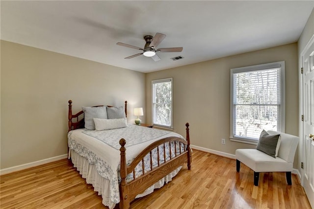 bedroom featuring light wood-type flooring, visible vents, baseboards, and ceiling fan