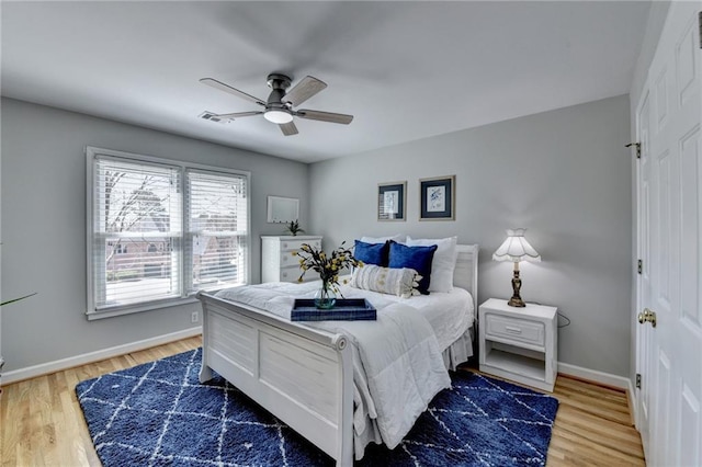 bedroom with ceiling fan, wood finished floors, visible vents, and baseboards