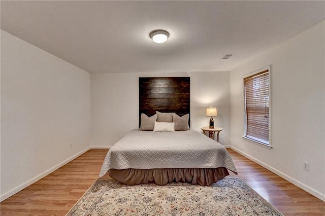 bedroom with visible vents, wood finished floors, and baseboards