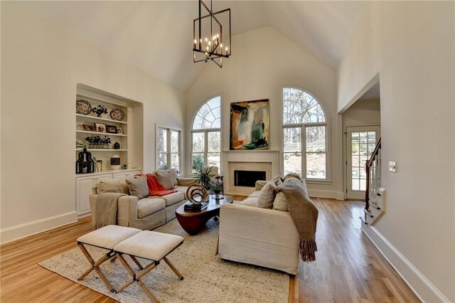 living room with a fireplace, wood finished floors, a wealth of natural light, and high vaulted ceiling