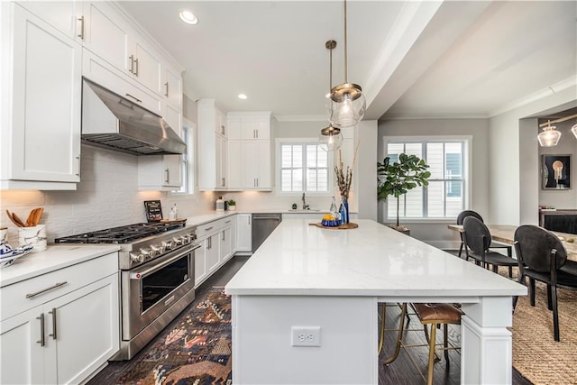 kitchen with pendant lighting, white cabinets, appliances with stainless steel finishes, a center island, and backsplash