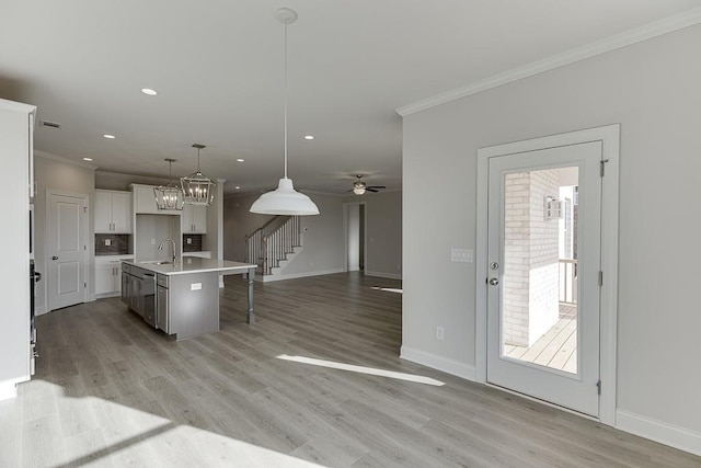 kitchen featuring sink, decorative light fixtures, white cabinetry, a kitchen island with sink, and a breakfast bar